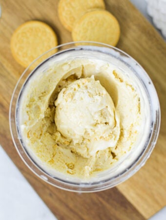 A Ninja Creami pint container filled with Ninja Creami Golden Oreo Ice Cream, with an ice cream scoop resting on top.