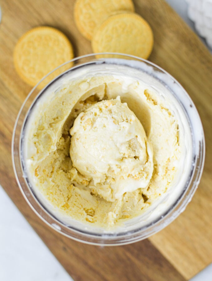 A Ninja Creami pint container filled with Ninja Creami Golden Oreo Ice Cream, with an ice cream scoop resting on top.