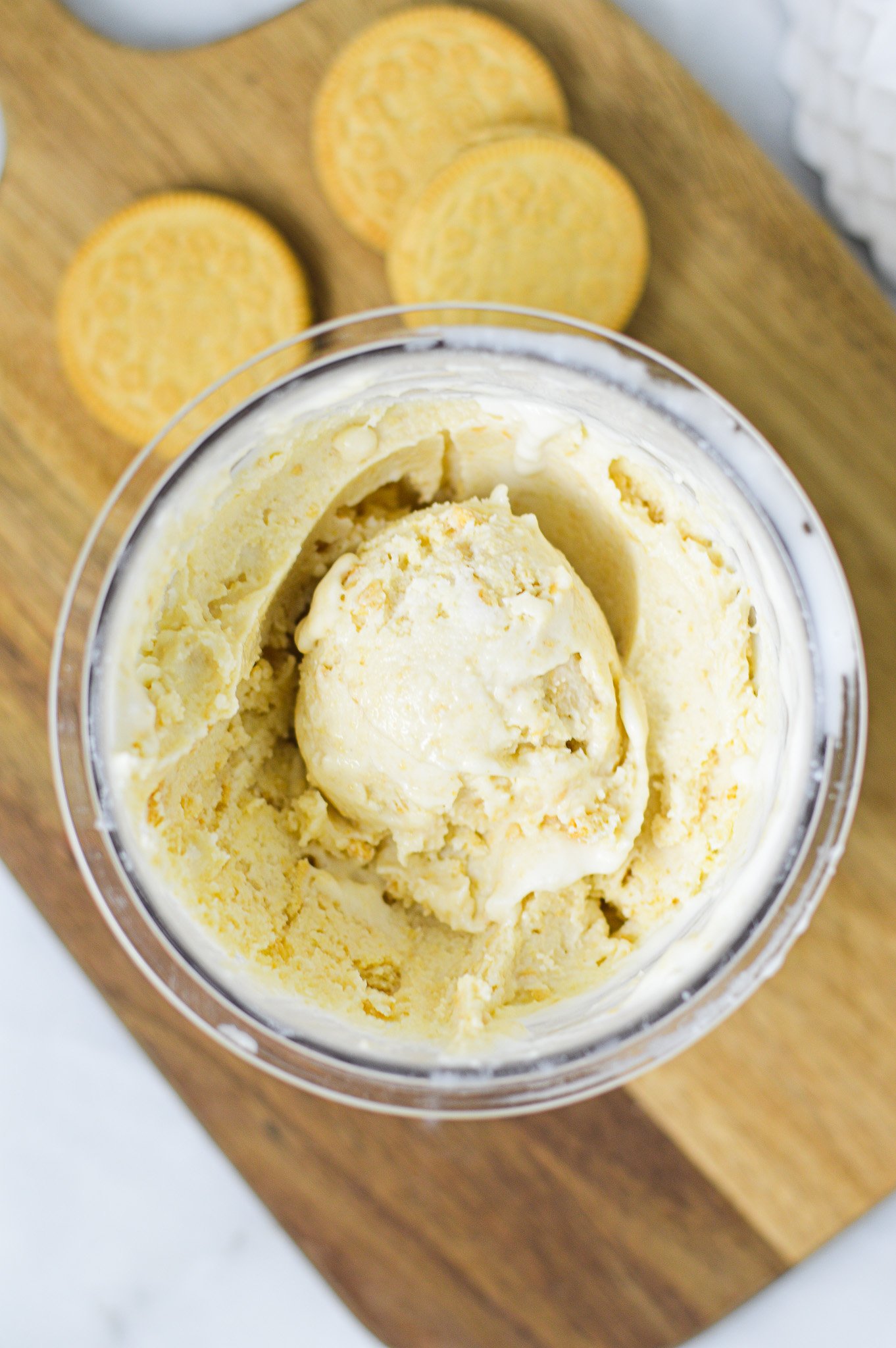 A Ninja Creami pint container filled with Ninja Creami Golden Oreo Ice Cream, with an ice cream scoop resting on top.
