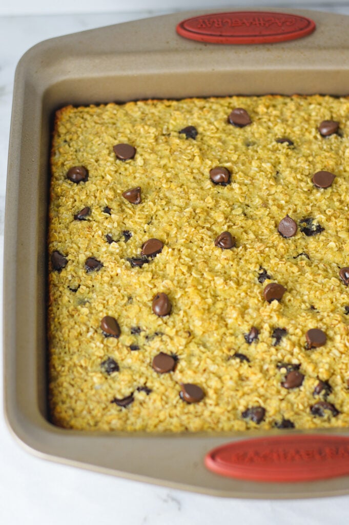 A square dish filled with Chocolate Chip Baked Oatmeal, with the golden brown top and melty chocolate chips giving it that just baked look.