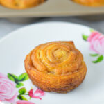 Golden brown Cinnamon Sugar Crescent Roll Muffins on a small plate, with a muffin tin filled with freshly baked muffins.