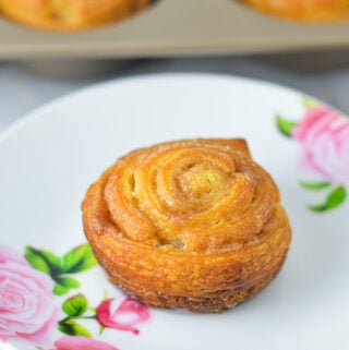 Golden brown Cinnamon Sugar Crescent Roll Muffins on a small plate, with a muffin tin filled with freshly baked muffins.