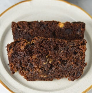 Two slices of homemade Triple Chocolate Banana Bread, with semi-sweet and white chocolate chips studded in the rich chocolate bread.