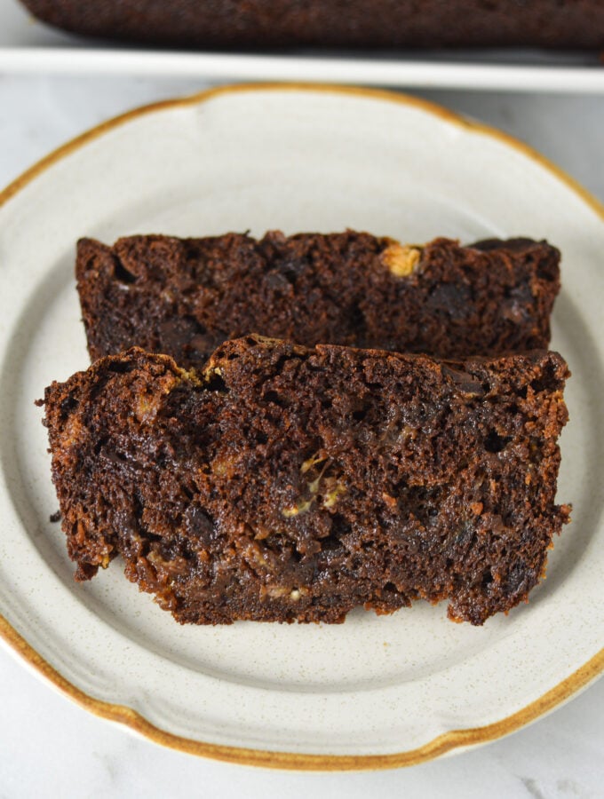 Two slices of homemade Triple Chocolate Banana Bread, with semi-sweet and white chocolate chips studded in the rich chocolate bread.