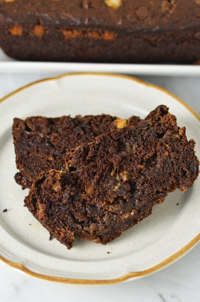 A couple of slices of Triple Chocolate Banana Bread on a small plate, with the melted chocolate clearly visible in this decadent dessert.
