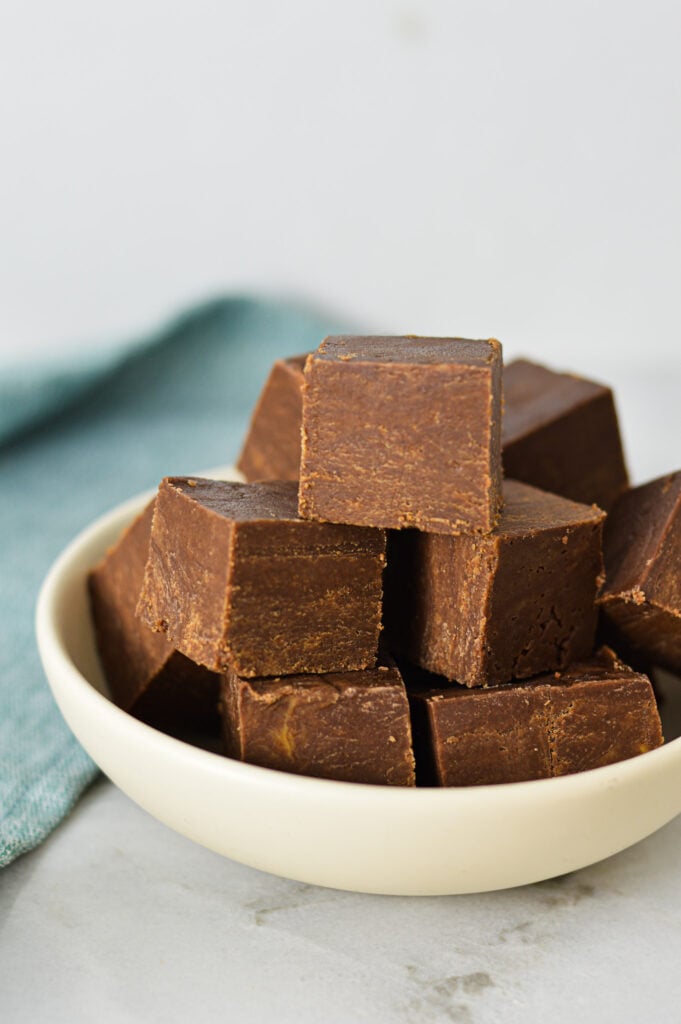 Rich and creamy Chocolate Peanut Butter Fudge squares on a small ceramic plate.