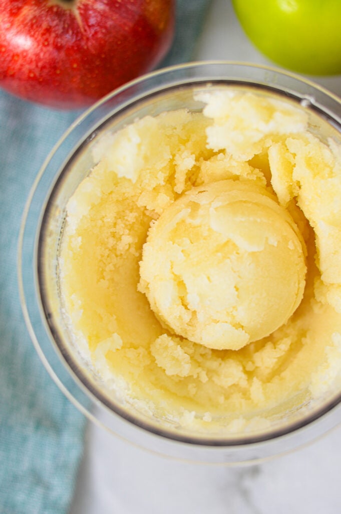 A Ninja Creami pint filled with Ninja Creami Apple Italian Ice, with a scoop of the icy Italian ice clearly visible.