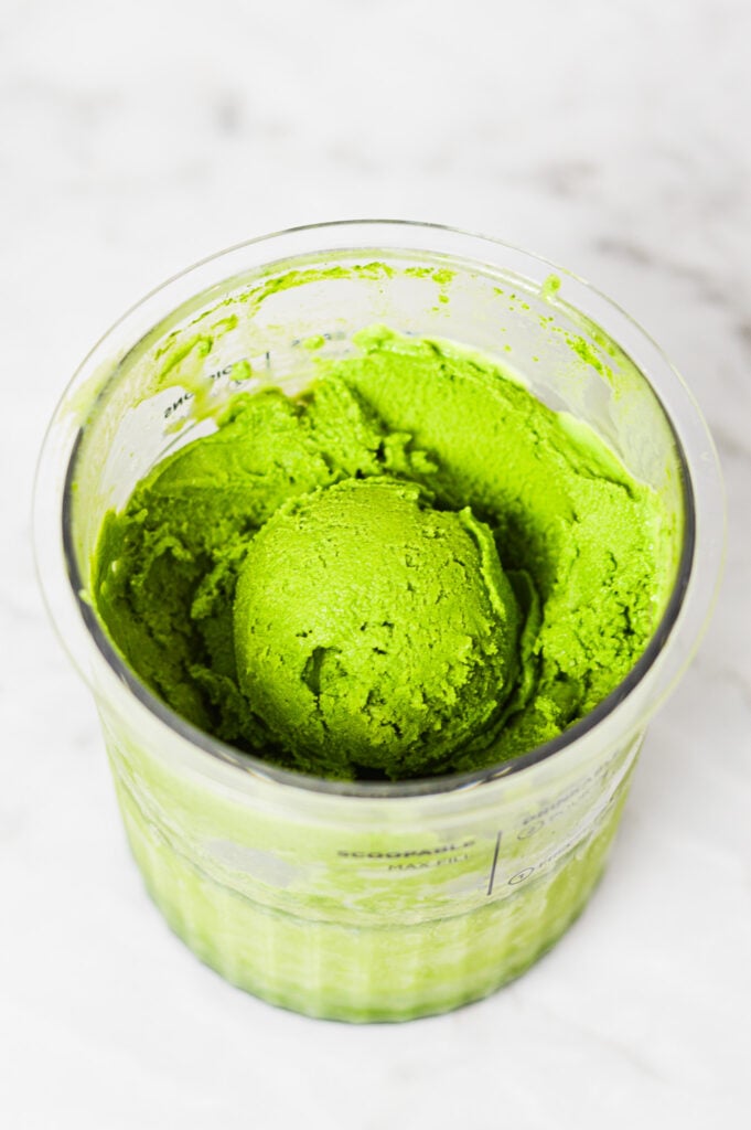 A Ninja Creami container filled with Ninja Creami Matcha Ice Cream, with an ice cream scoop on top clearly showing the creamy texture of the homemade ice cream.