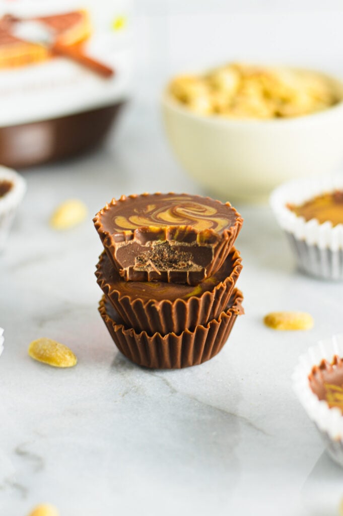 A stack of Peanut Butter Swirl Nutella Cups with a bite taken out of the top chocolate cup showing the creamy texture of the sweet dessert.
