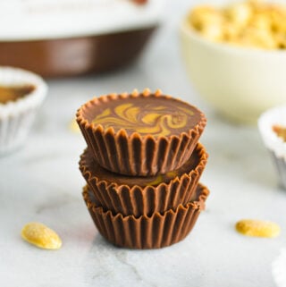 A stack of Peanut Butter Swirl Nutella Cups with some salted peanuts and a jar of Nutella in the background.