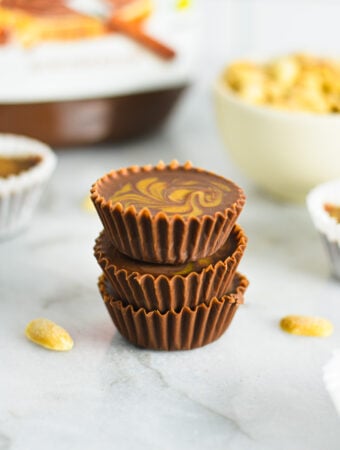 A stack of Peanut Butter Swirl Nutella Cups with some salted peanuts and a jar of Nutella in the background.
