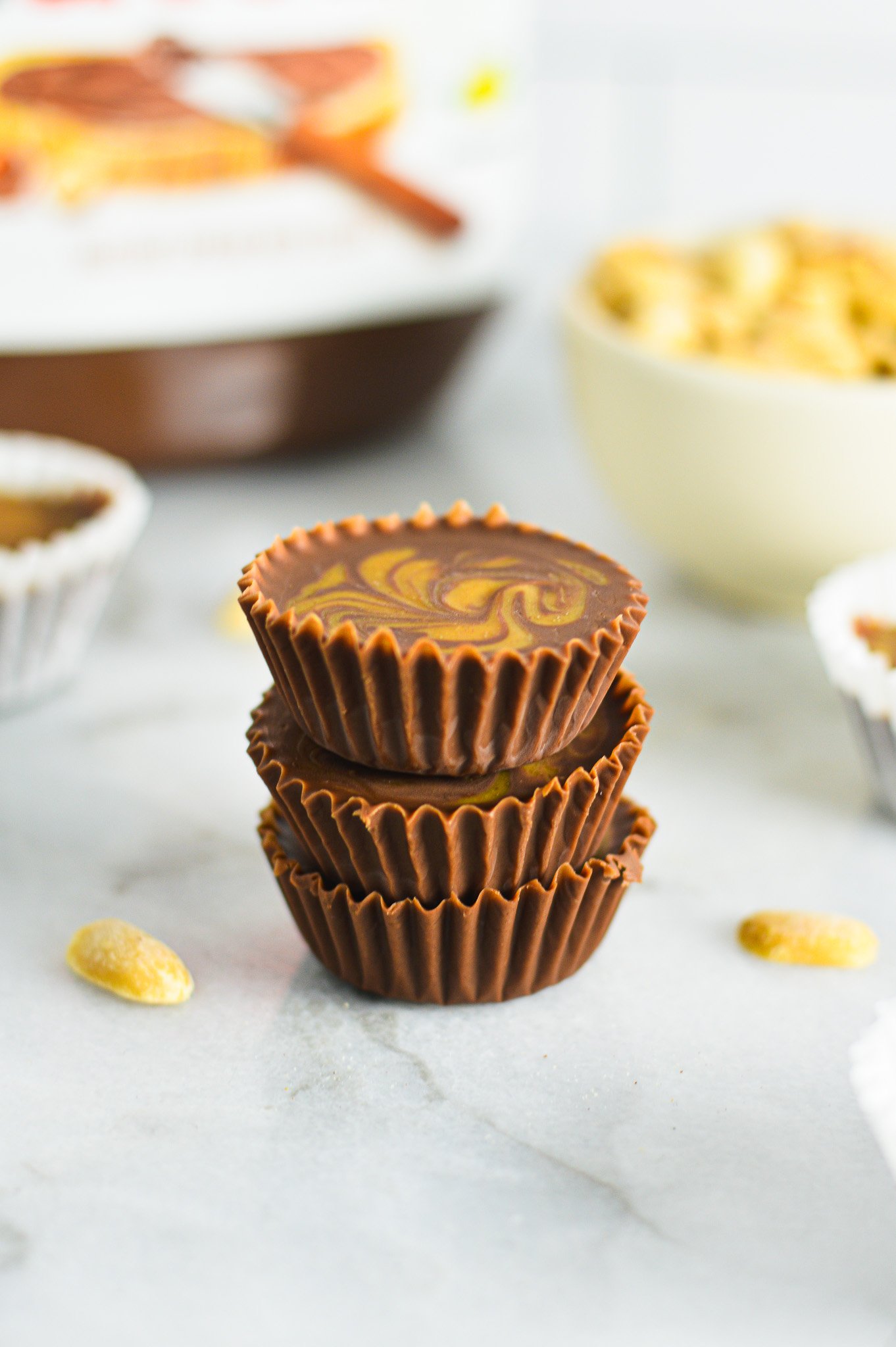 A stack of Peanut Butter Swirl Nutella Cups with some salted peanuts and a jar of Nutella in the background.