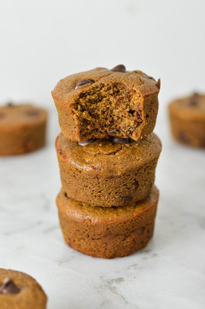 A stack of Protein Mocha Chocolate Chip Muffins with a bite taken out of the top muffin, showing the fluffy texture.