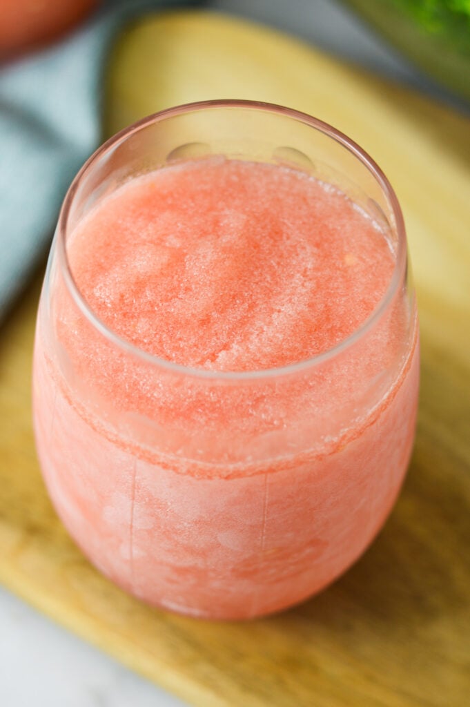A tall glass of Frozen Watermelon Daiquiri, with its bright pink color and slushy texture in full display.