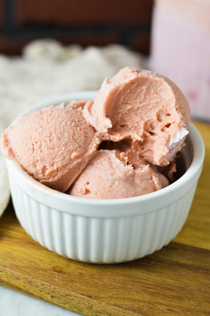 A scoop taken out of a bowl of Ninja Creami Cherry Ice Cream, showing its silky smooth texture.