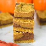 A stack of freshly baked Pumpkin Nutella Bars, with the layers of rich chocolate hazelnut spread showing between the pumpkin base.
