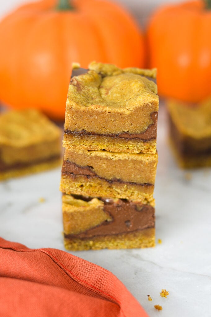 A stack of freshly baked Pumpkin Nutella Bars, with the layers of rich chocolate hazelnut spread showing between the pumpkin base.