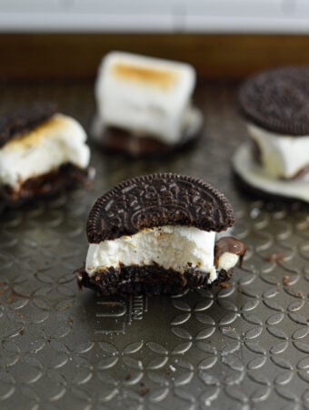 Some S'moreos on a baking sheet, with toasted marshmallows and melted chocolate sandwiched between two crunchy Oreo cookies.