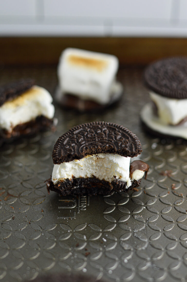 Some S'moreos on a baking sheet, with toasted marshmallows and melted chocolate sandwiched between two crunchy Oreo cookies.