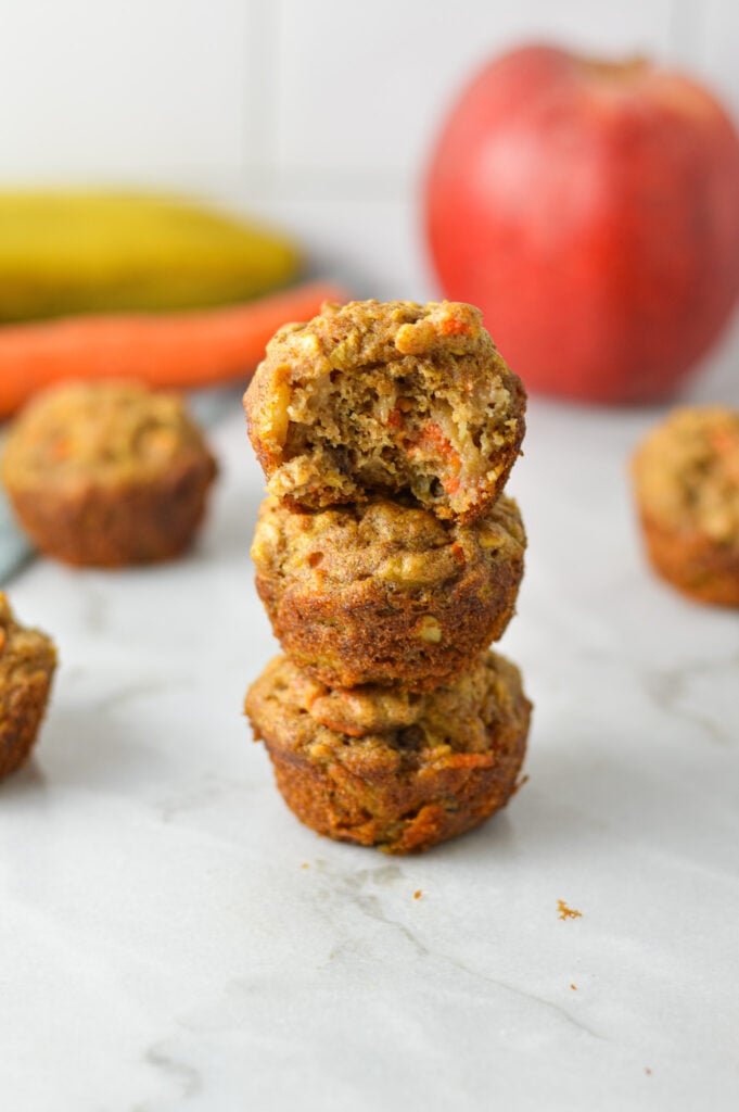 A stack of ABC Baby Mini Muffins with a bite taken out of the top muffin, showing it's hearty texture.