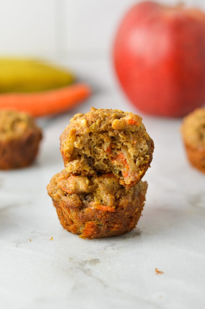 A stack of ABC Baby Mini Muffins, with a bite taken out of the top muffin showing the soft texture.