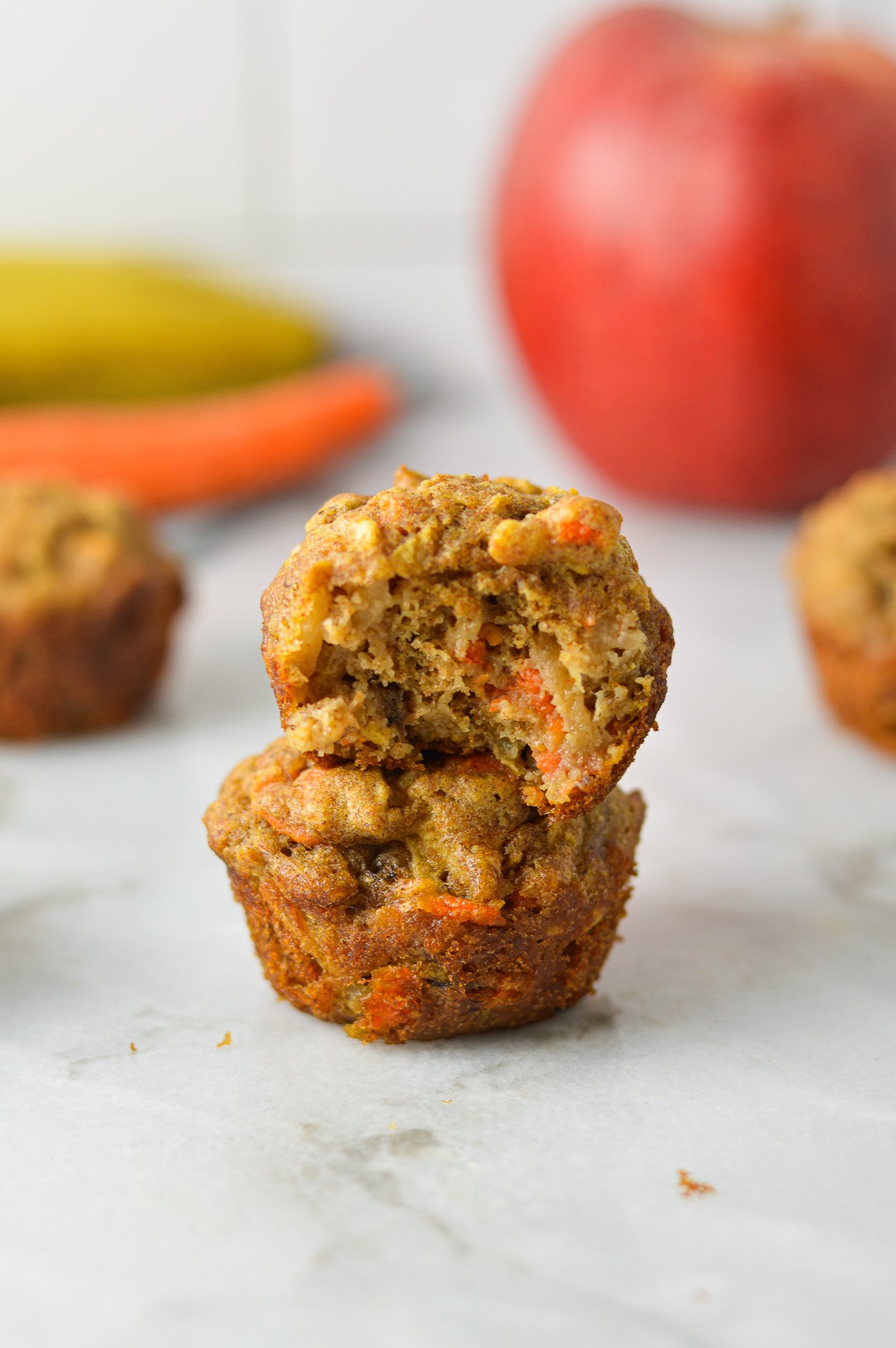 A stack of ABC Baby Mini Muffins, with a bite taken out of the top muffin showing the soft texture.
