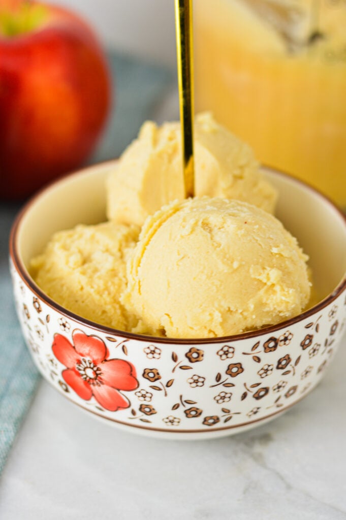 A bowl full of Ninja Creami Caramel Apple Sorbet, with a gold spoon sticking out of the creamy dessert.