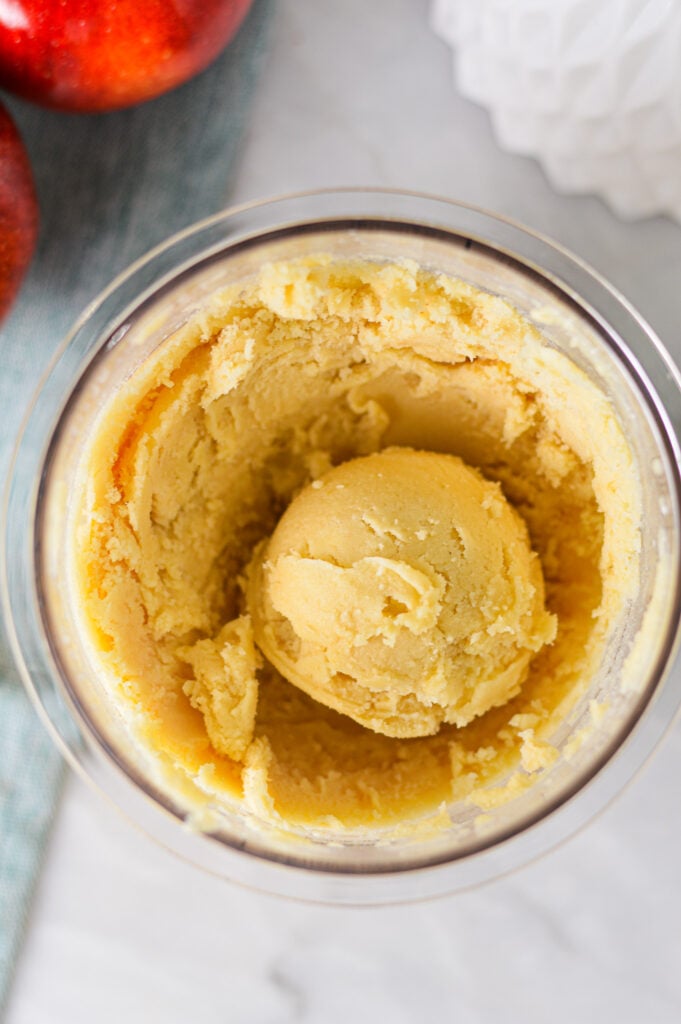 A Ninja Creami pint container filled with Ninja Creami Caramel Apple Sorbet, with a scoop in the center showing its smooth texture.