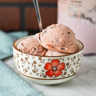 A small bowl filled with Ninja Creami Cherry Chocolate Chunk Ice Cream, with a spoon sticking out of the creamy ice cream.