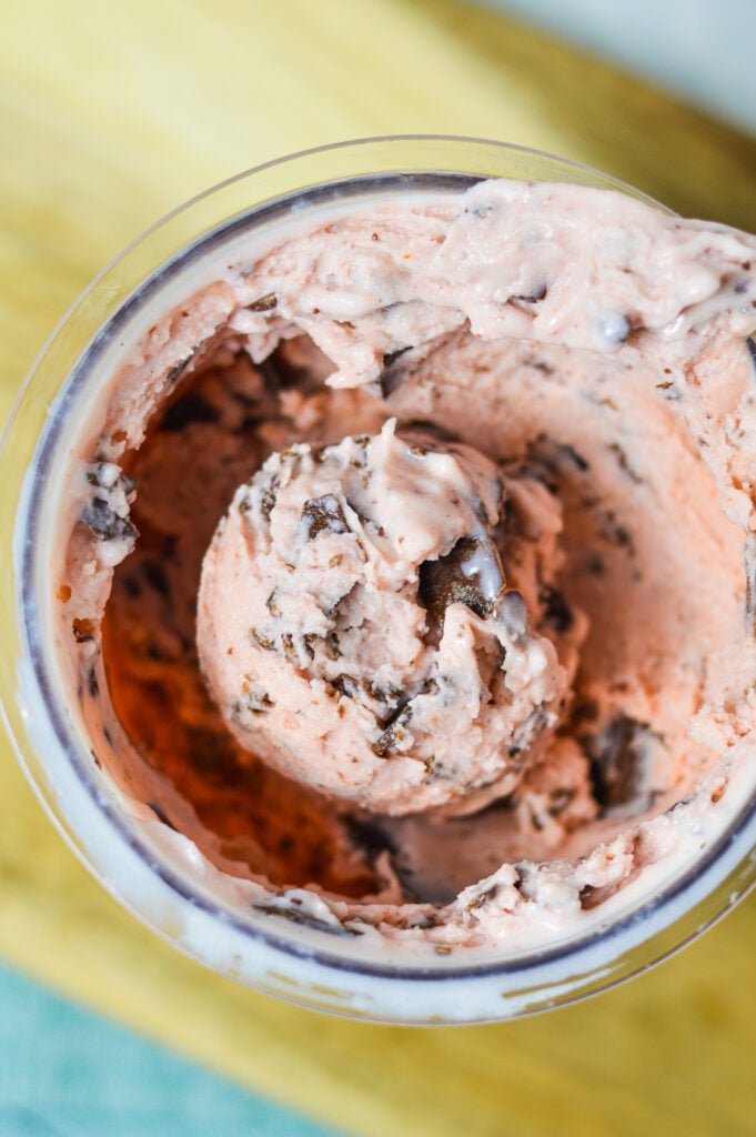 A Ninja Creami pint container filled with Ninja Creami Cherry Chocolate Chunk Ice Cream, with the chocolate chunks clearly visible inside the cherry ice cream.