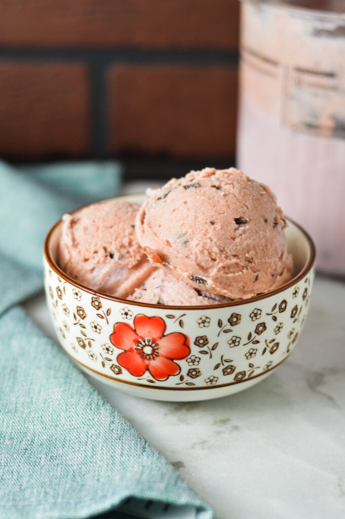 A small bowl of Chocolate Chunk cherry ice cream made in a Ninja Creami machine on a granite surface.