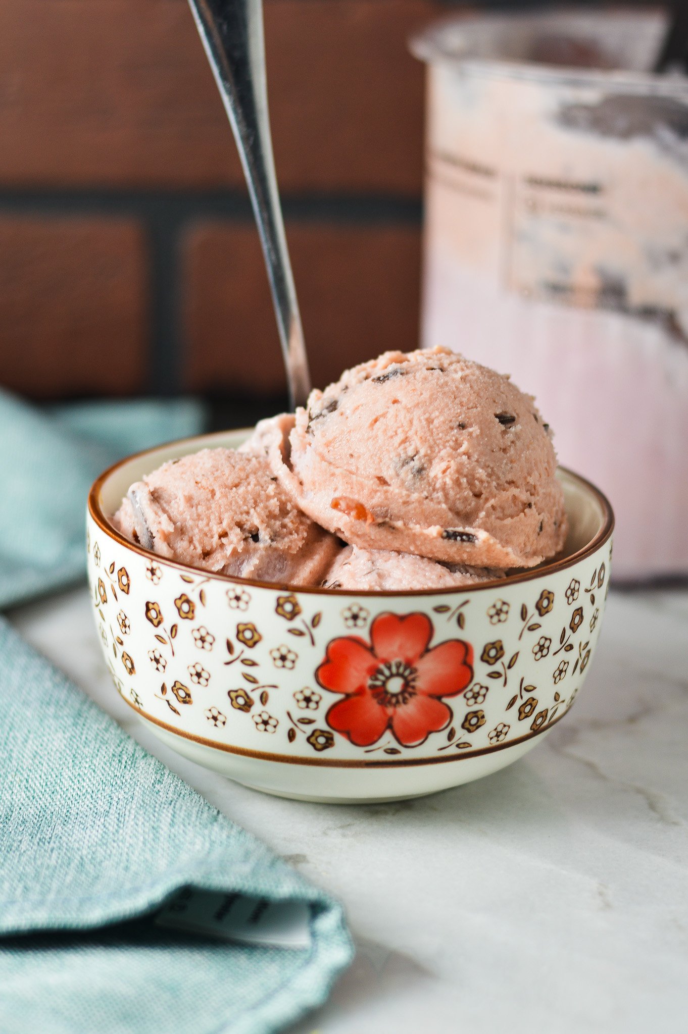 A small bowl filled with Ninja Creami Cherry Chocolate Chunk Ice Cream, with a spoon sticking out of the homemade ice cream.