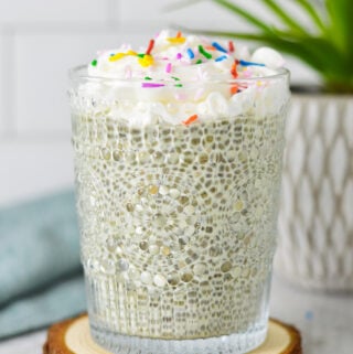 A glass cup filled with Birthday Cake Chia Pudding, topped with whipped cream and candy sprinkles.