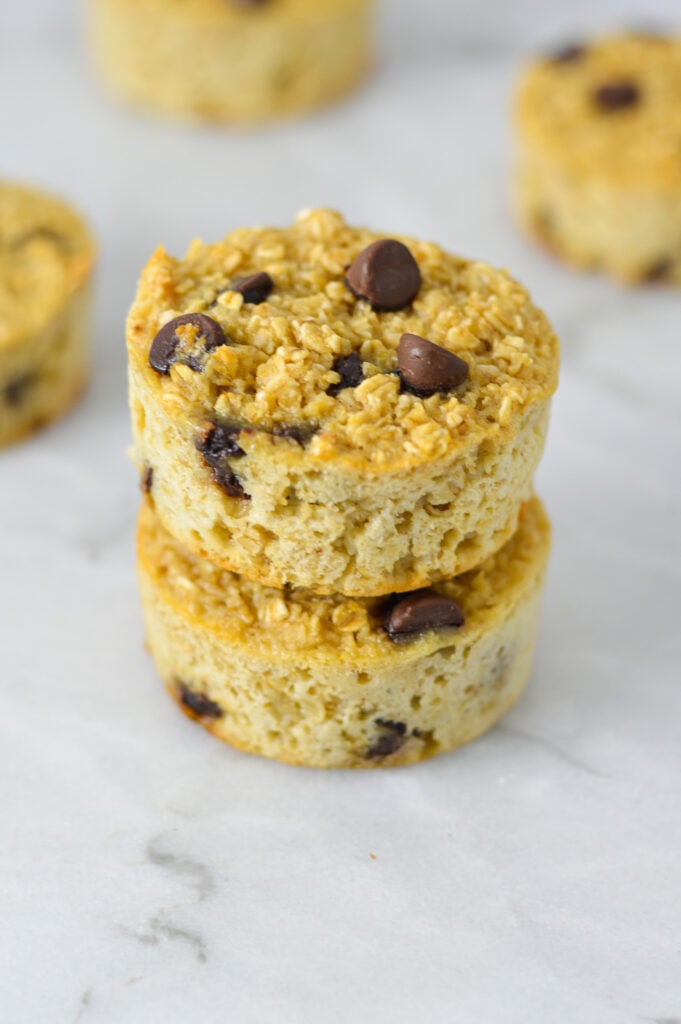 A stack of Chocolate Chip Baked Oatmeal Cups, with the semi-sweet chocolate chips visible on top of the hearty oatmeal cups.