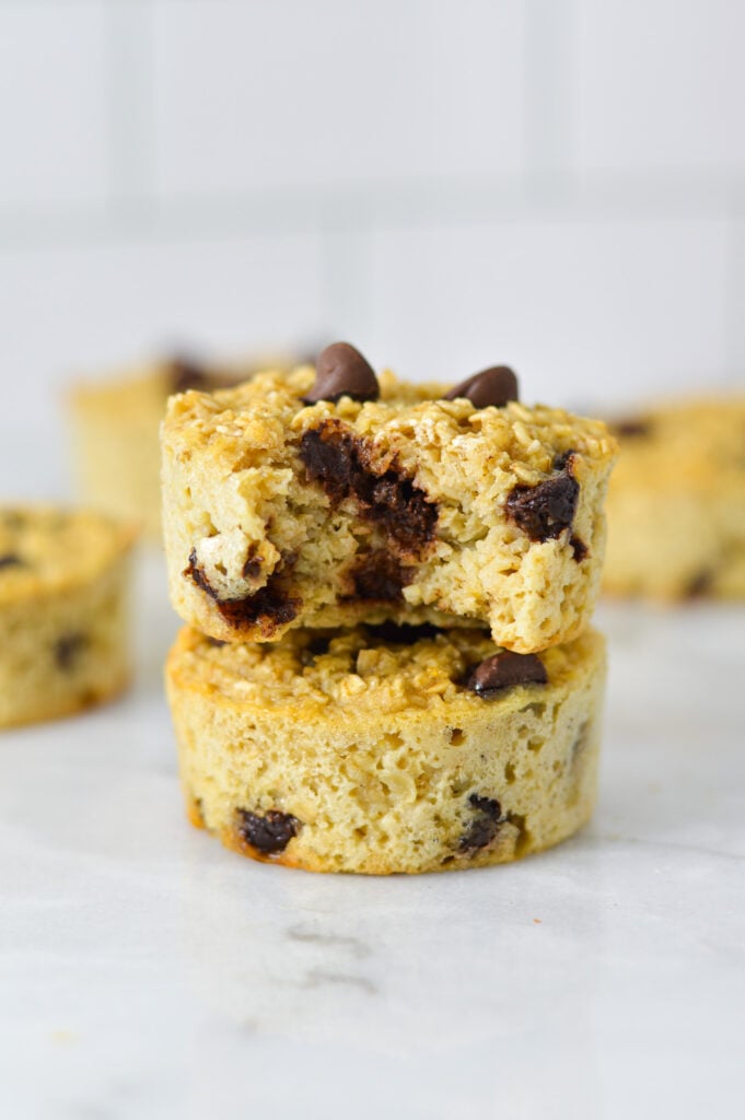 A stack of Chocolate Chip Baked Oatmeal Cups with a bite taken out of the top oatmeal cup, revealing the hearty texture.