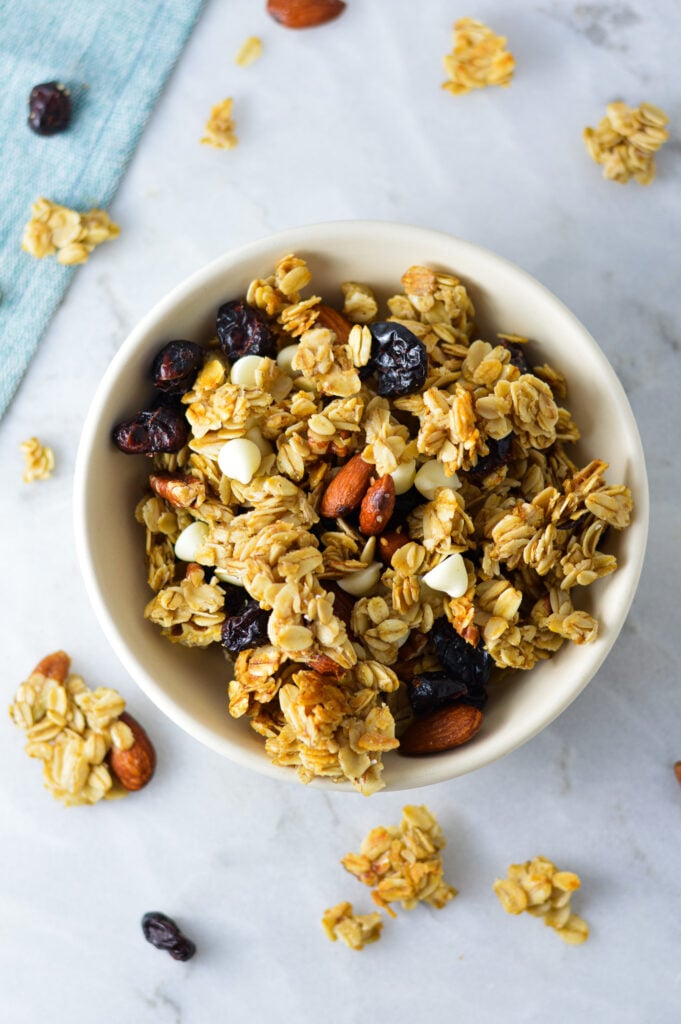 A small bowl of Cranberry White Chocolate Granola, with the pecans, craisins and white chocolate chips clearly visible amongst the chunky granola.