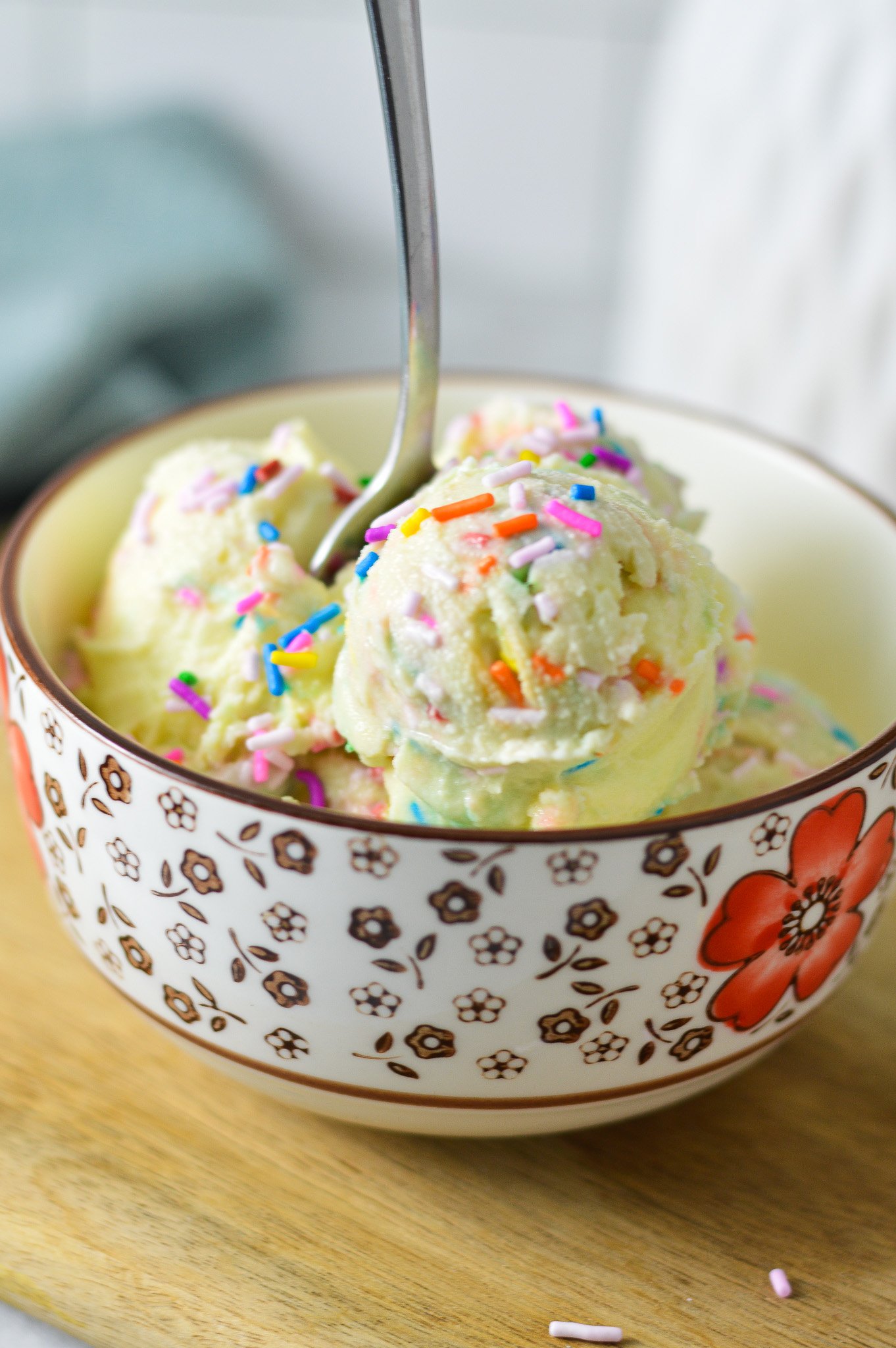 A small bowl filled with homemade Ninja Creami Birthday Cake Ice Cream, with a small spoon sticking out of the creamy ice cream.