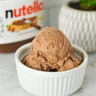 Homemade Ninja Creami Nutella Ice Cream in a small ramekin, with a jar of Nutella in the background.