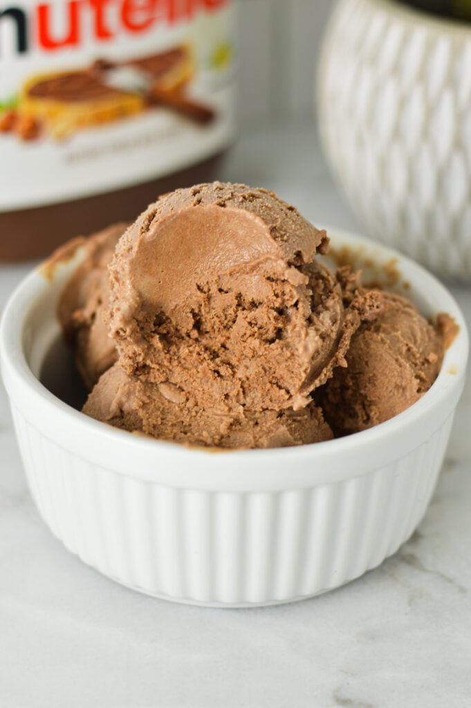 Some scoops of creamy Nutella ice cream made in the Ninja Creami machine, with a scoop taken out showing the rich texture.