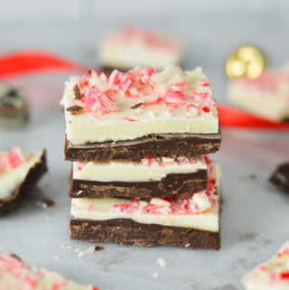 A stack of Peppermint Bark, with some red ribbon and gold bells in the background, giving a holiday season vibe.