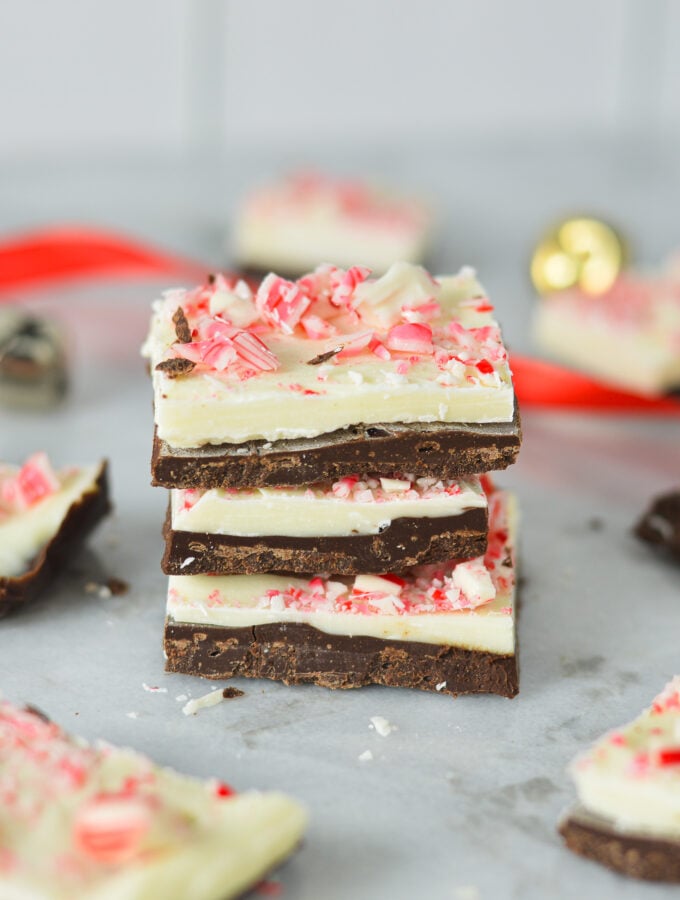 A stack of Peppermint Bark, with some red ribbon and gold bells in the background, giving a holiday season vibe.
