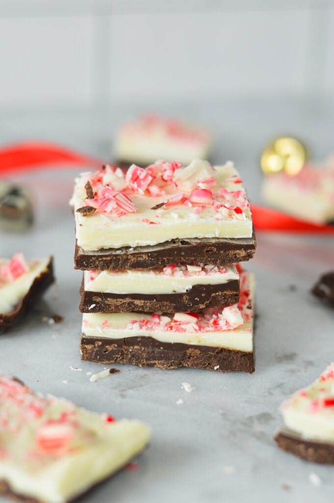 A stack of Peppermint Bark, with some red ribbon and gold bells in the background, giving a holiday season vibe.