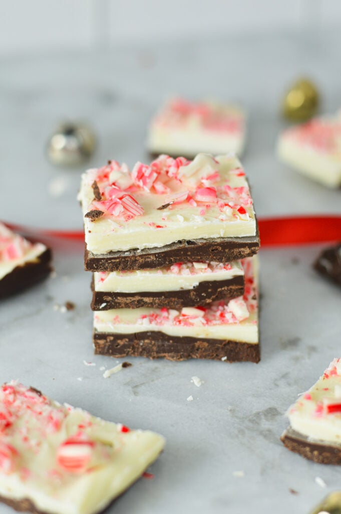 A stack of homemade Peppermint Bark, with the crushed candy canes on top of the white chocolate and milk chocolate layer clearly visible.