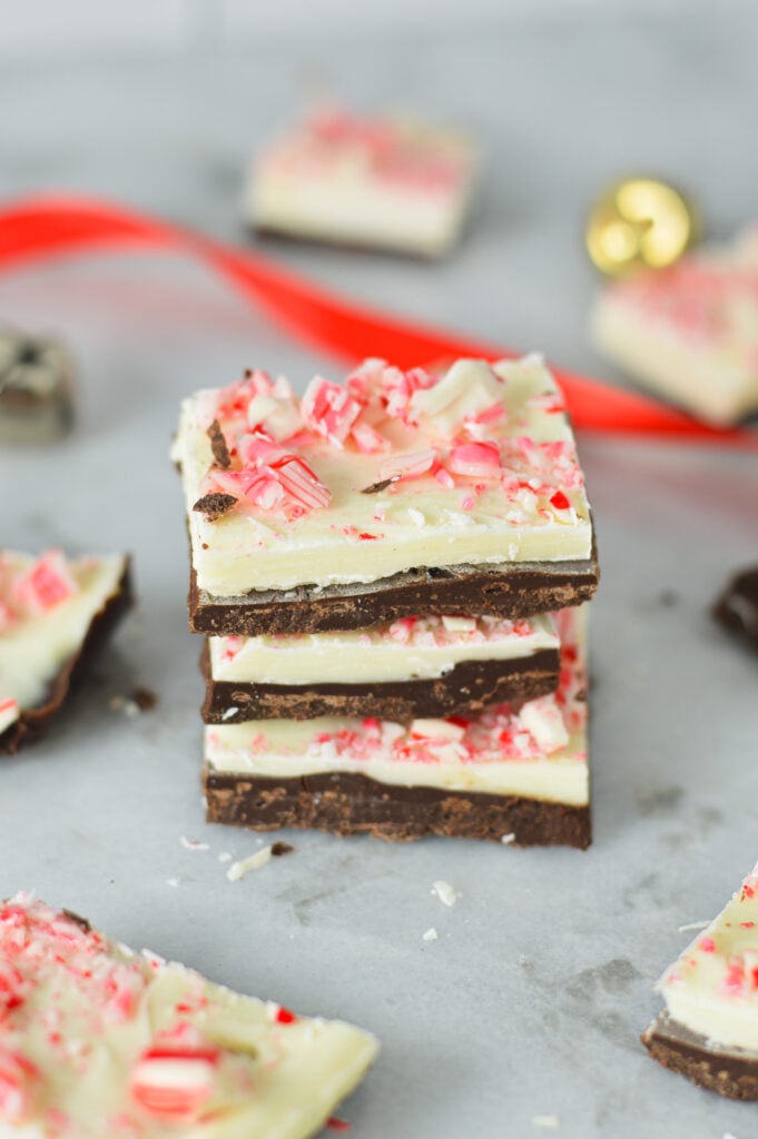 A stack of Chocolate Peppermint Bark with some Christmas bells and present ribbon in the background, giving the scene a real Christmas feel.