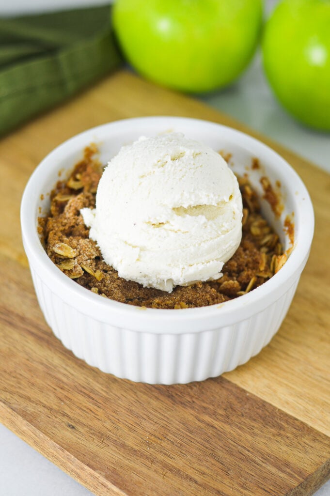 A single serving Apple Crisp topped with a scoop of ice cream.