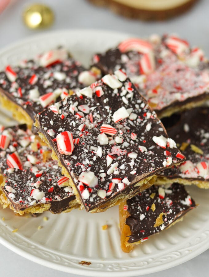 A small plate filled with Candy Cane Saltine Toffee, topped with crushed candy cane on top of the melted chcolate layer.