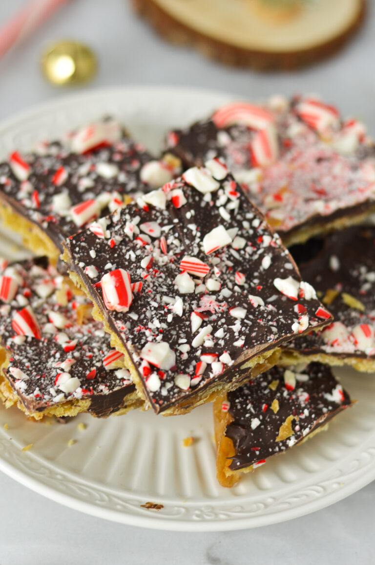 A small plate filled with Candy Cane Saltine Toffee, topped with crushed candy cane on top of the melted chcolate layer.