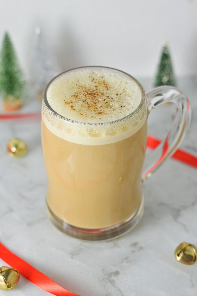 A large coffee mug filled with rich Eggnog Latte, with warm spices sprinkled on top of the festive drink.