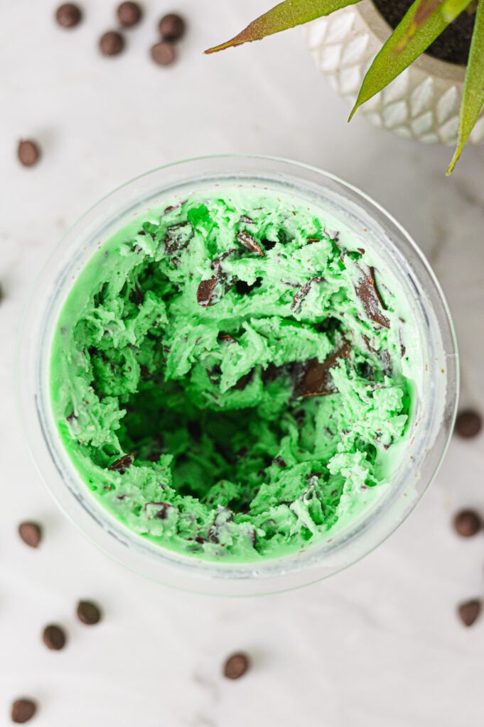 A Ninja Creami container filled with Ninja Creami Mint Chocolate Chunk Ice Cream, with the chunks of chocolate clearly visible in the creamy green ice cream.