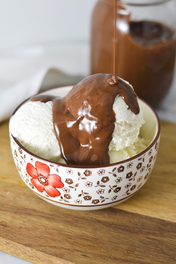 A bowl of ice cream with some Nutella Magic Shell being drizzled on top.